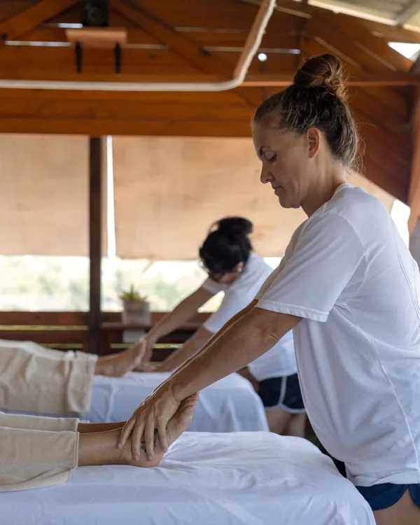 Terapeuta trabajando la pierna de un cliente en la terraza de Calma